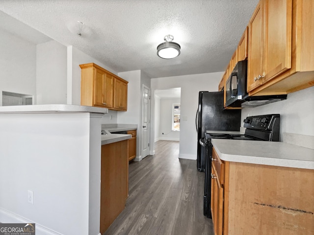 kitchen featuring wood-type flooring, kitchen peninsula, a textured ceiling, and black appliances