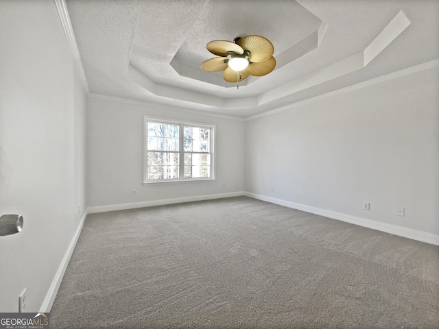 spare room with ceiling fan, carpet flooring, a tray ceiling, ornamental molding, and a textured ceiling