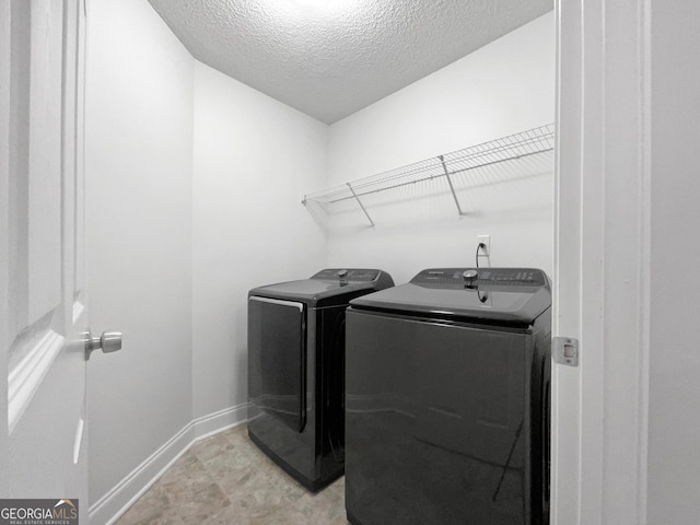 washroom featuring washing machine and dryer and a textured ceiling