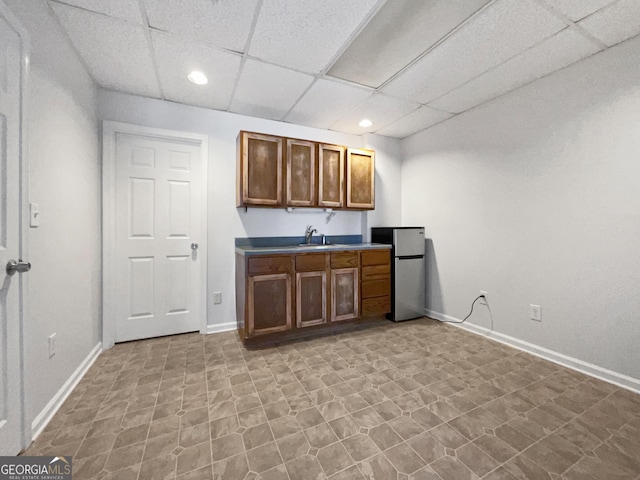 kitchen featuring sink, a paneled ceiling, and stainless steel fridge