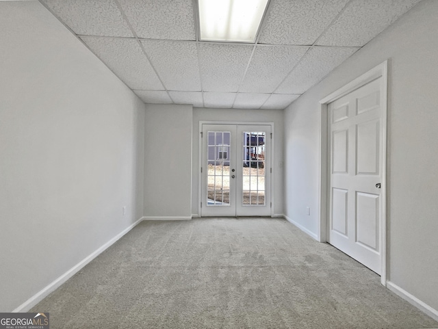 spare room with a paneled ceiling, light colored carpet, and french doors