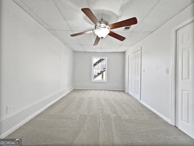 carpeted empty room featuring a paneled ceiling and ceiling fan