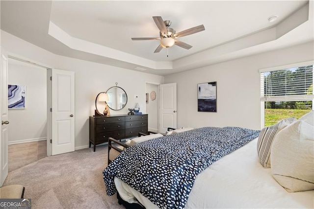 bedroom featuring ceiling fan, a raised ceiling, and carpet