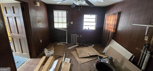 interior space featuring ceiling fan and wooden walls