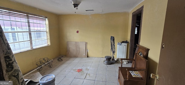 tiled spare room featuring a textured ceiling and a healthy amount of sunlight