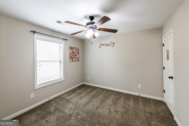 carpeted spare room featuring a ceiling fan, visible vents, and baseboards