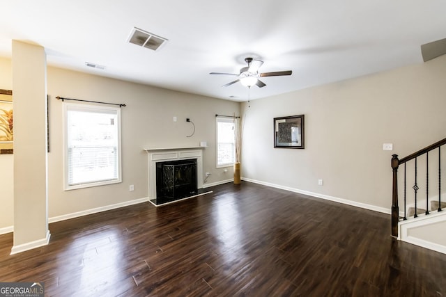 unfurnished living room with dark wood-style floors, stairs, visible vents, and a premium fireplace