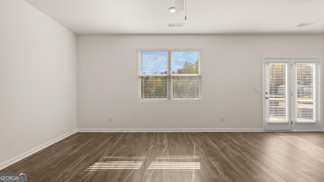 spare room featuring dark hardwood / wood-style flooring and a wealth of natural light