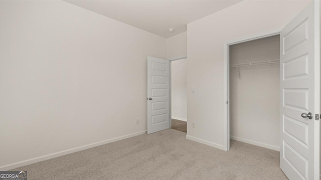 unfurnished bedroom with light colored carpet and a closet