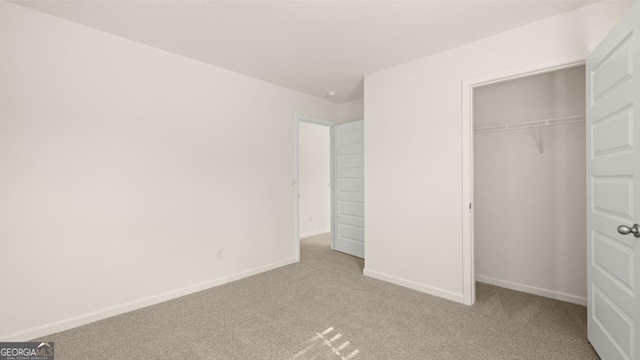 unfurnished bedroom with light carpet and a closet