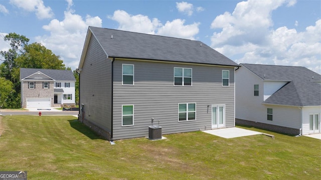 back of house with central AC unit, a garage, a patio area, and a yard