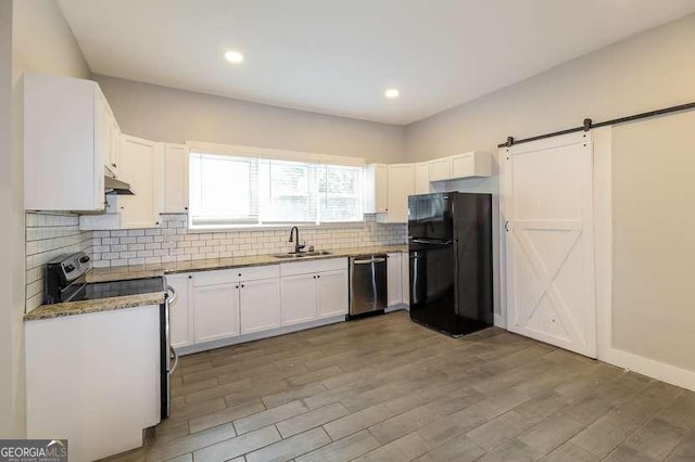 kitchen with sink, white cabinets, stainless steel appliances, a barn door, and backsplash