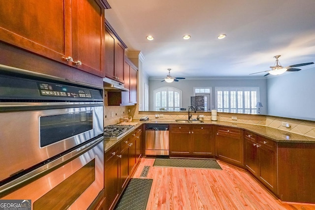 kitchen with stainless steel appliances, a sink, backsplash, and a peninsula