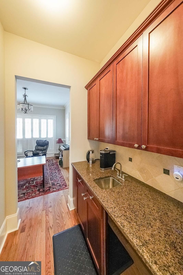 kitchen with stone counters, baseboards, a sink, and light wood finished floors