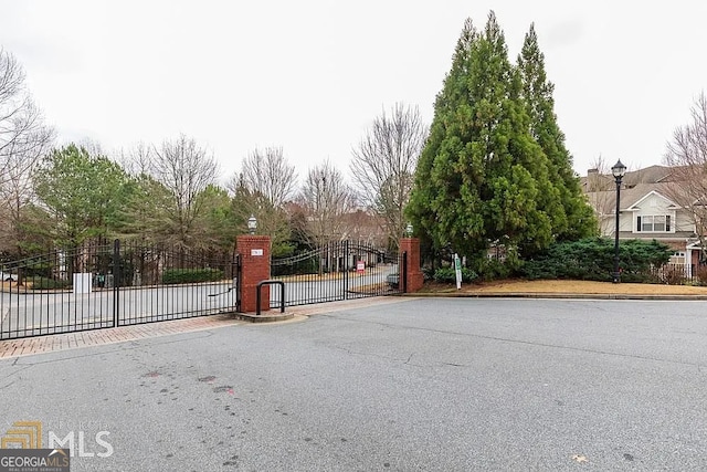 view of street with curbs, a gated entry, and a gate