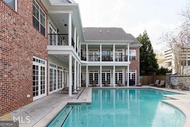 rear view of house with a fenced in pool and a patio area