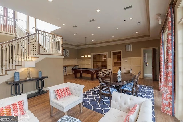 living area featuring light wood-style floors, visible vents, crown molding, and stairs