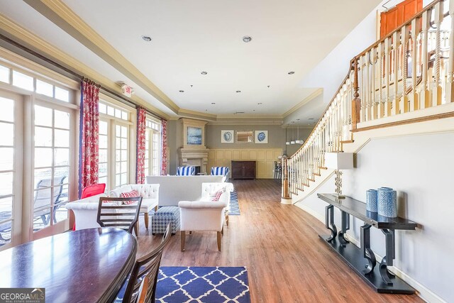 living area featuring baseboards, stairway, wood finished floors, and crown molding