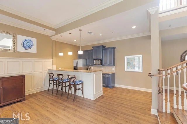 kitchen featuring appliances with stainless steel finishes, a kitchen breakfast bar, decorative light fixtures, and light wood-type flooring