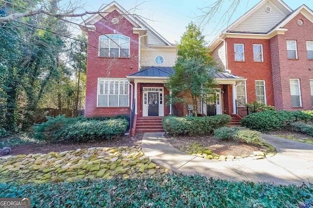 view of front of home featuring a standing seam roof, metal roof, and brick siding