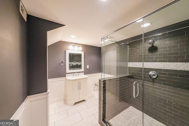 bathroom featuring a wainscoted wall, visible vents, a stall shower, vaulted ceiling, and vanity