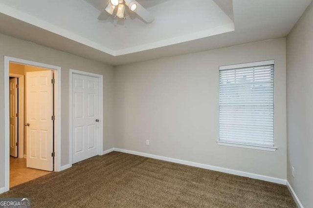 unfurnished bedroom with a tray ceiling, carpet floors, and ceiling fan