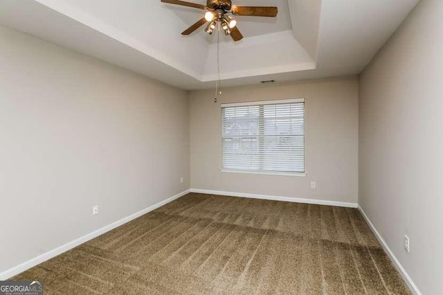 carpeted spare room featuring ceiling fan and a tray ceiling