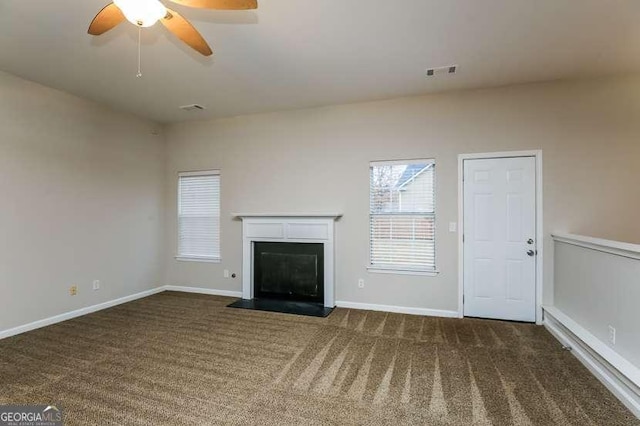 unfurnished living room featuring ceiling fan and dark carpet