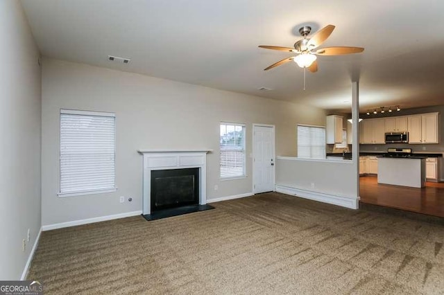 unfurnished living room featuring ceiling fan and dark carpet