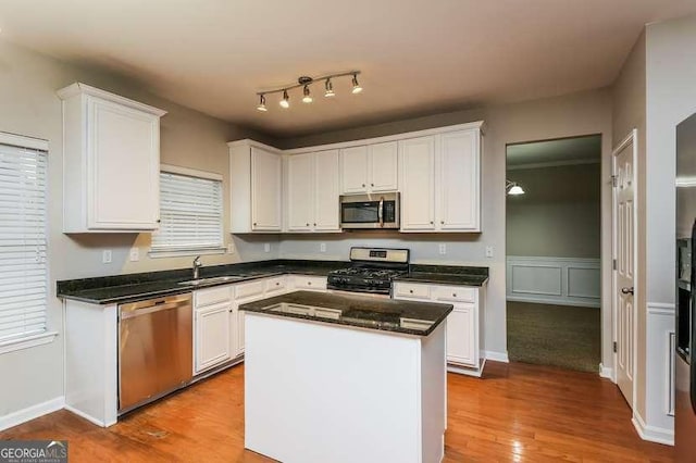 kitchen featuring white cabinetry, stainless steel appliances, a center island, and light wood-type flooring