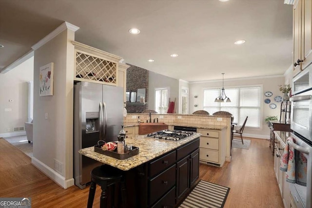 kitchen featuring crown molding, a breakfast bar, appliances with stainless steel finishes, kitchen peninsula, and light wood-type flooring