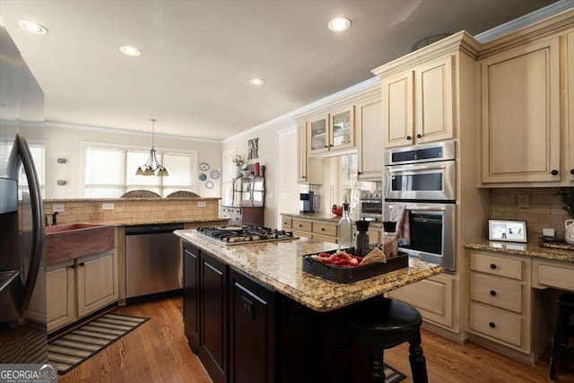 kitchen with pendant lighting, light stone counters, stainless steel appliances, and a kitchen island