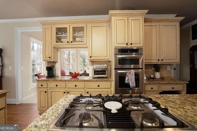 kitchen with crown molding, gas cooktop, double oven, tasteful backsplash, and light stone countertops