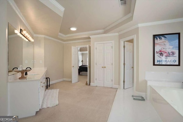 bathroom with a raised ceiling, vanity, ornamental molding, and a bath