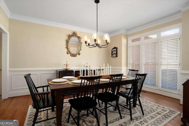 dining space featuring wood-type flooring, crown molding, and an inviting chandelier