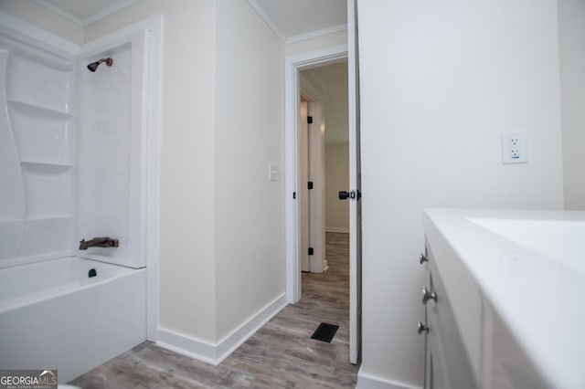 bathroom featuring wood-type flooring, shower / bathtub combination, crown molding, and vanity