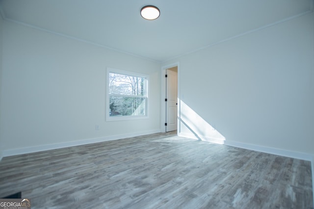 spare room with hardwood / wood-style flooring and crown molding