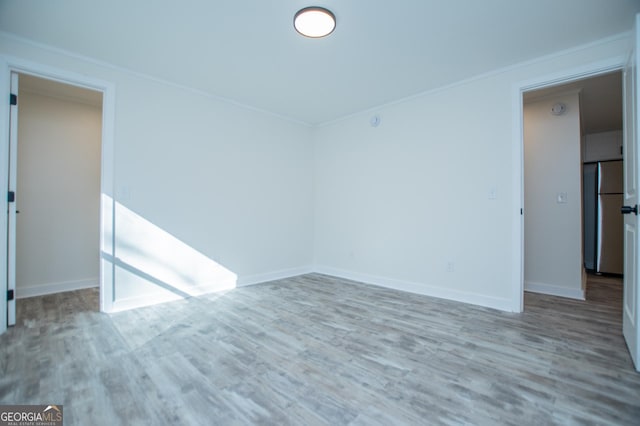 empty room with ornamental molding and light hardwood / wood-style flooring