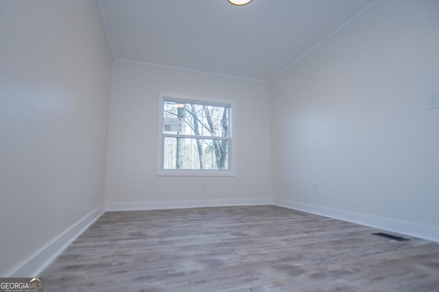 unfurnished room with crown molding, hardwood / wood-style flooring, and lofted ceiling