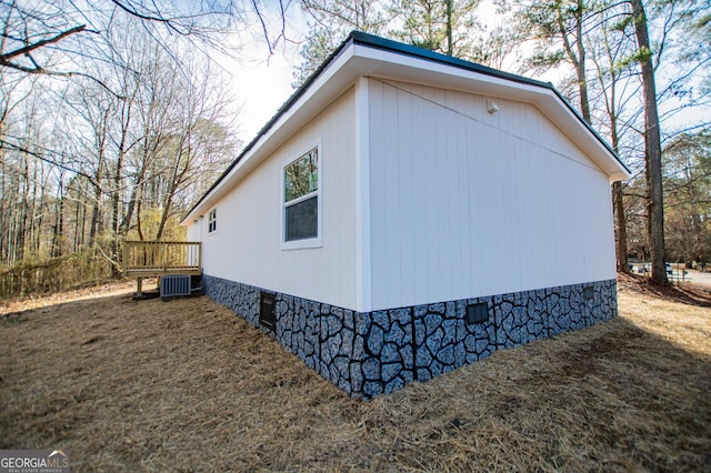 view of side of home with a wooden deck and central air condition unit