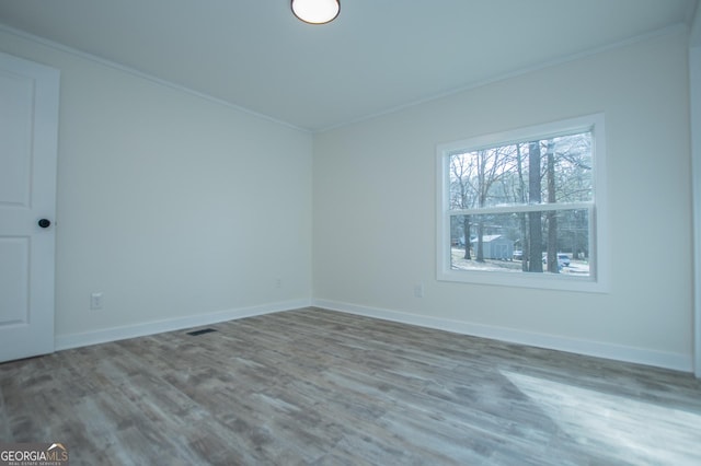 spare room with hardwood / wood-style flooring and crown molding