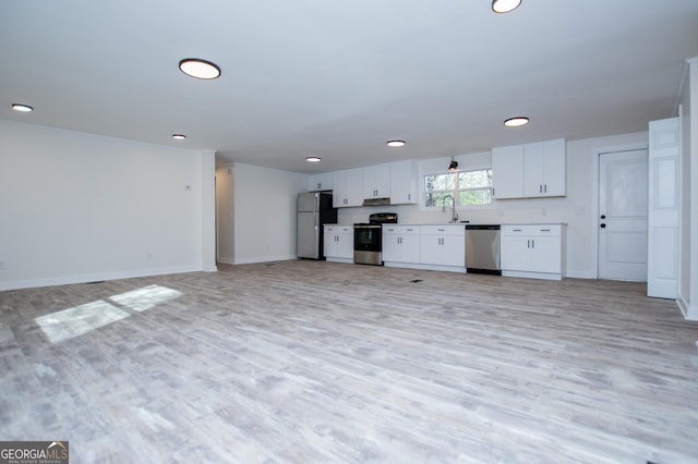 kitchen with appliances with stainless steel finishes, sink, white cabinets, and light hardwood / wood-style floors