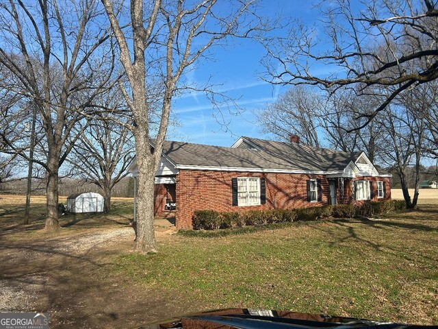 view of front of house with a storage shed and a front lawn