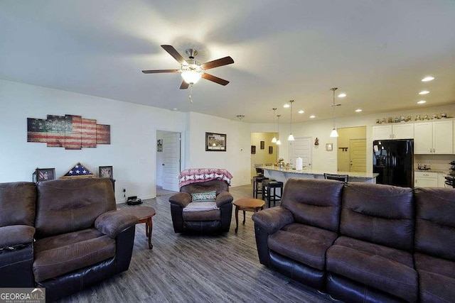 living room featuring dark wood-type flooring and ceiling fan