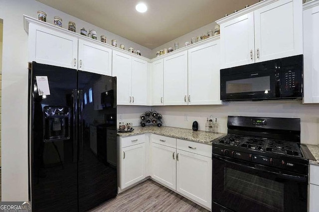 kitchen with light stone counters, light hardwood / wood-style flooring, black appliances, and white cabinets