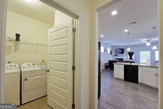 laundry room with sink, light hardwood / wood-style flooring, washer and dryer, and ceiling fan