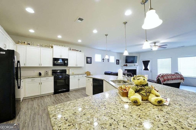 kitchen with white cabinetry, sink, decorative light fixtures, and black appliances