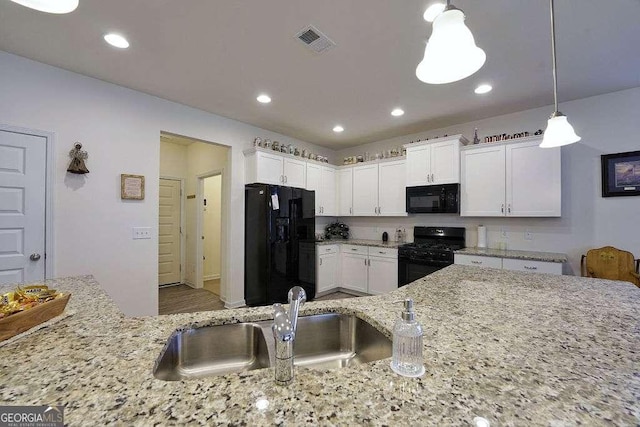 kitchen featuring decorative light fixtures, white cabinetry, sink, light stone counters, and black appliances