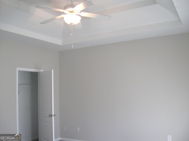 unfurnished bedroom featuring ceiling fan, a raised ceiling, and a closet