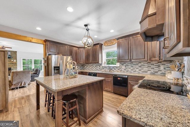 kitchen featuring sink, a center island, stainless steel fridge with ice dispenser, hanging light fixtures, and dishwasher